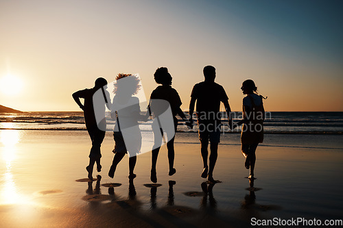 Image of Beach, sunset and back of friends holding hands with freedom, bond and fun on summer vacation. Ocean, silhouette and rear view of people together at the sea for travel, holiday or adventure in Miami