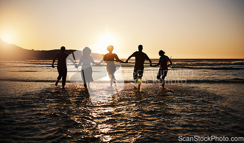 Image of Water splash, sunset and friends holding hands at a beach with freedom, running or fun vacation rear view. Ocean, silhouette and people shadow in solidarity at the sea for travel, bond or celebration