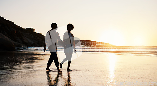 Image of Beach, sunset and silhouette couple walking on sand, holding hands and enjoy romantic time together. Wellness, summer freedom and dark shadow of people bonding, talking and relax on tropical date