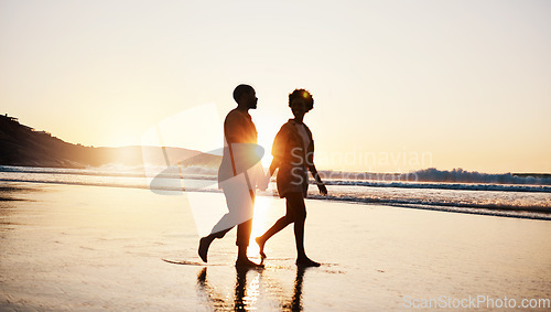 Image of Beach sunset, silhouette and couple walking, holding hands and enjoy romantic conversation, freedom and travel holiday. Love, sea and dark shadow of people bonding, talking and relax on tropical date