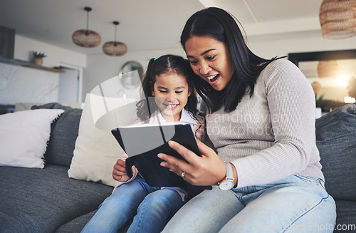 Image of Tablet, surprise and a mother on the sofa with her daughter in the living room of their home together. Wow, family or children with a mother and girl looking at social media or a good news email