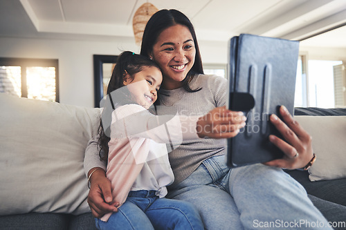 Image of Tablet, selfie and a mother on the sofa with her daughter in the living room of their home together. Photograph, family or children with a mother and girl taking a profile picture for social media