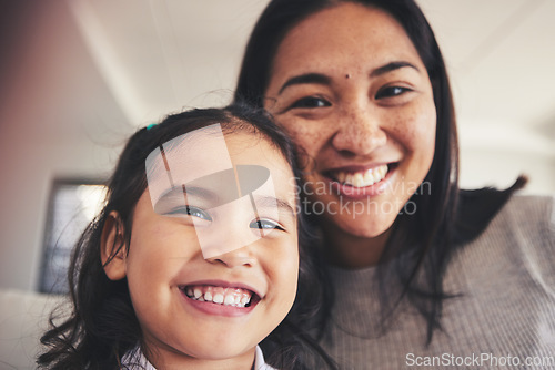 Image of Selfie, smile and portrait of a girl with her mother bonding in the living room of their home. Happy, love and face headshot of Asian child taking a picture with her young mom at their family house.