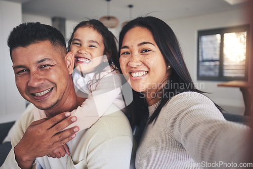 Image of Selfie, happy and portrait of a family with a smile bonding in the living room of their home. Together, love and young happy parents taking a picture with their sweet girl child for memories in house