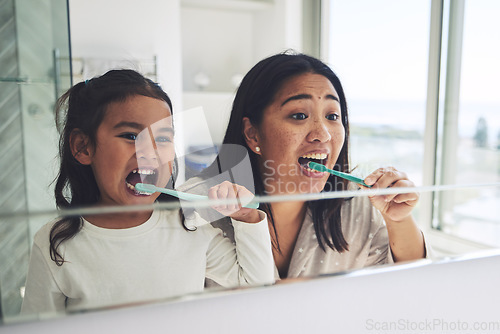 Image of Mother, child and brushing teeth in dental hygiene, morning routine or healthcare together by mirror in bathroom. Happy mom and daughter cleaning mouth in tooth whitening, oral or gum care at home