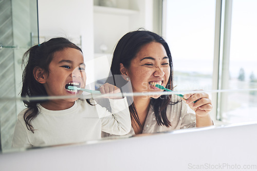 Image of Mother, child and brushing teeth in morning routine, dental hygiene or healthcare together by mirror in bathroom. Happy mom and daughter cleaning mouth in tooth whitening, oral or gum care at home