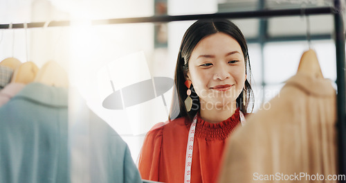 Image of Fashion designer, woman and clothes choice on rack in shop for choosing outfit. Boutique, store and smile of happy Asian tailor or seamstress checking selection of clothing for inventory in wardrobe.