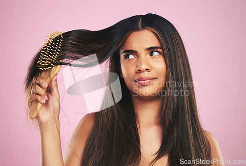 Image of Woman, hair and worry with brush in studio for texture, shine and keratin on pink background. Natural beauty, face and young model thinking with comb tools for tangled hairstyle, knot and treatment