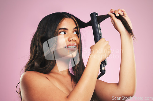 Image of Woman, hair and care with iron in studio for beauty, cosmetic treatment and shine on pink background. Face of young model, hairstyle and heating equipment of electrical tools for aesthetic texture