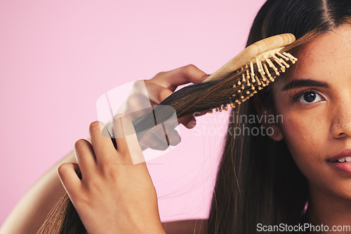 Image of Hair care, brush portrait and woman with natural beauty and salon treatment in a studio. Bamboo hairdresser tool and Brazilian hairstyle with female model face from Brazil with pink background