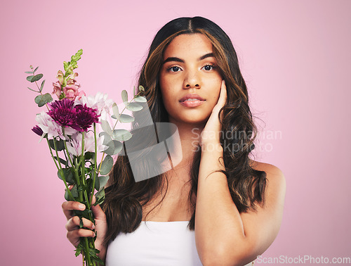 Image of Woman, flowers and portrait in studio for skincare, cosmetics and natural aesthetic on pink background. Face, model and eco beauty with floral plants, sustainability and bouquet for vegan dermatology