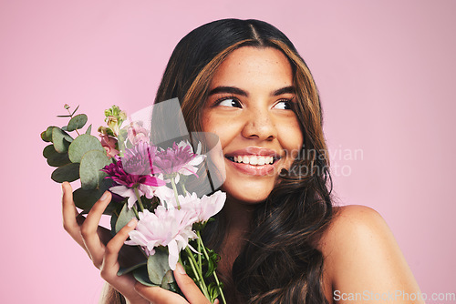 Image of Woman, flowers and bouquet in studio for skincare, cosmetics and natural aesthetic on pink background. Face, happy model and thinking of eco beauty with floral plants, sustainability and dermatology