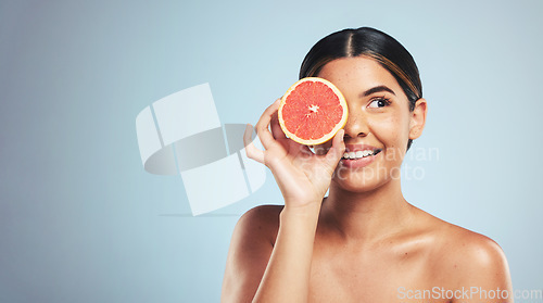 Image of Skincare, grapefruit and woman in studio for natural cosmetic, treatment or beauty on grey background. Citrus, facial and model with fruit for vegan, detox and vitamin c, glowing skin or collagen