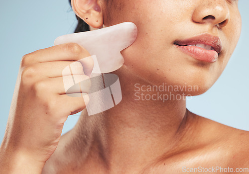 Image of Skincare, gua sha and woman with face massage on studio for anti aging, wellness and circulation on grey background. Stone, facelift and beauty model with rose quartz for lymphatic drainage facial