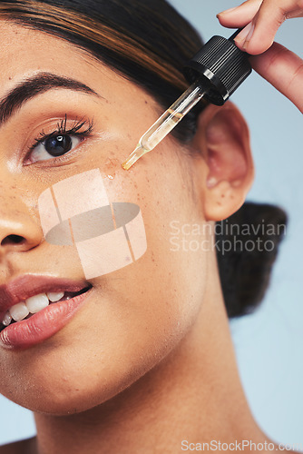 Image of Woman, face oil and portrait in studio for beauty of aesthetic skincare, dermatology and makeup on blue background. Closeup of model with dropper for facial cosmetics, hyaluronic acid or liquid serum