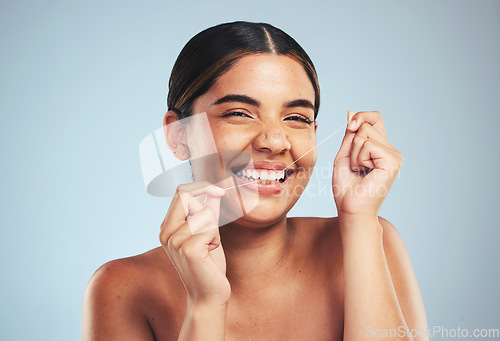 Image of Woman, portrait and smile to floss teeth in studio for dental hygiene, care and gum gingivitis on blue background. Happy model cleaning mouth with oral thread for fresh breath, healthy habit or tooth