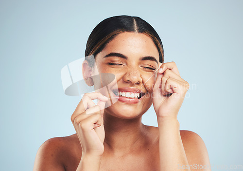 Image of Woman, smile and floss teeth in studio for dental hygiene, care and gum gingivitis on blue background. Happy female model cleaning mouth with oral thread for fresh breath, healthy habit and grooming