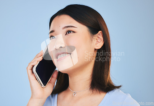 Image of Asian woman, thinking and phone call in studio with chat, networking and smile by blue background. Young Japanese student, girl and smartphone for contact, mobile connection and memory with ideas