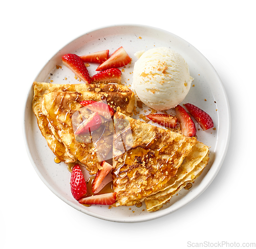 Image of crepes decorated with honey, strawberries and ice cream