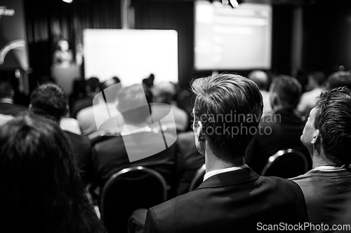 Image of Speaker giving a talk in conference hall at business event. Rear view of unrecognizable people in audience at the conference hall. Business and entrepreneurship concept.