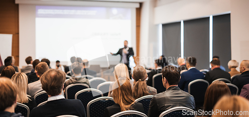 Image of Speaker giving a talk in conference hall at business event. Rear view of unrecognizable people in audience at the conference hall. Business and entrepreneurship concept.