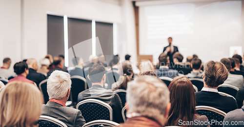 Image of Speaker giving a talk in conference hall at business event. Rear view of unrecognizable people in audience at the conference hall. Business and entrepreneurship concept.