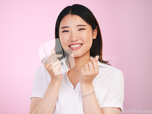 Image of Happy asian woman, portrait and love hands, sign or gesture in romance against a pink studio background. Face of female person smile in happiness with loving emoji or symbol for valentines day