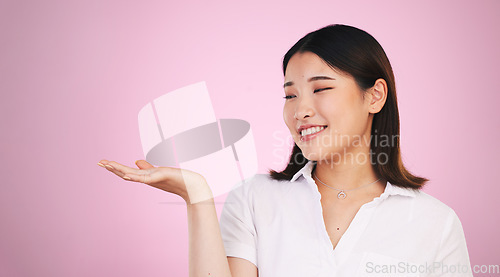 Image of Happy asian woman, palm and advertising on mockup space in marketing against a pink studio background. Female person with hands out in market show, presentation or product advertisement on mock up