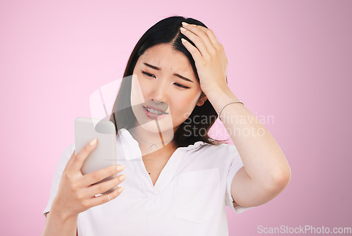 Image of Search, phone and anxiety with face of woman in studio for networking, communication and worry. Social media, news and frustrated with asian person on pink background for technology and mobile app