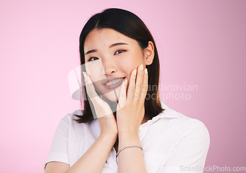 Image of Beauty, smile and hands on woman face in studio for self love, promotion and care on pink background. Happy, portrait and confident Japanese female model with acceptance, satisfaction and positivity