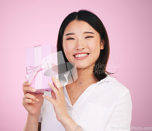 Image of Giveaway, Asian and portrait of woman giving present box happy for celebration isolated in a studio pink background. Gift, ribbon and person with happiness for surprise or prize package with smile