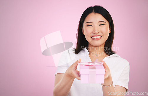 Image of Gift, Asian and portrait of woman giving present box happy for celebration isolated in a studio pink background. Giveaway, ribbon and person with happiness for surprise or prize package with smile