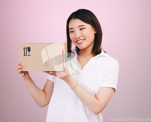 Image of Happy asian woman, box and delivery in online shopping, supply chain or logistics against a pink studio background. Excited female person or shopper with package, parcel or cargo in ecommerce