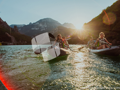 Image of A group of friends enjoying fun and kayaking exploring the calm river, surrounding forest and large natural river canyons during an idyllic sunset.