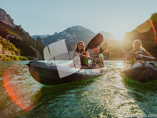 Image of A group of friends enjoying fun and kayaking exploring the calm river, surrounding forest and large natural river canyons during an idyllic sunset.