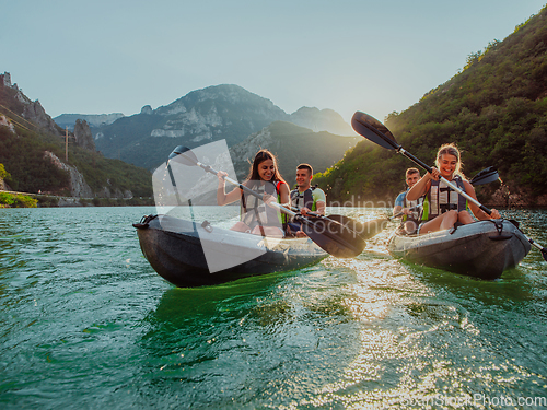 Image of A group of friends enjoying fun and kayaking exploring the calm river, surrounding forest and large natural river canyons during an idyllic sunset.