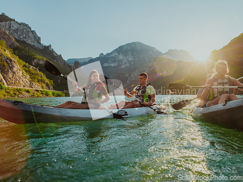 Image of A group of friends enjoying fun and kayaking exploring the calm river, surrounding forest and large natural river canyons during an idyllic sunset.