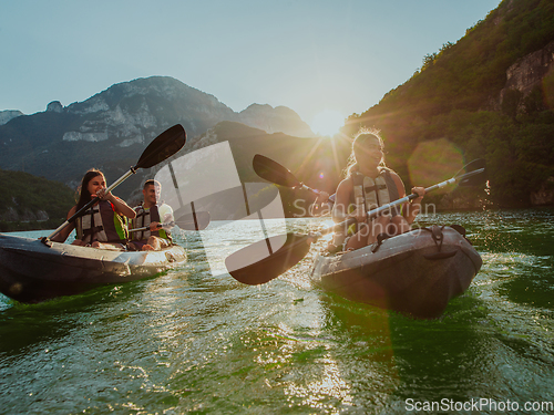 Image of A group of friends enjoying fun and kayaking exploring the calm river, surrounding forest and large natural river canyons during an idyllic sunset.