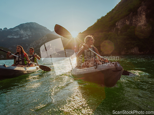 Image of A group of friends enjoying fun and kayaking exploring the calm river, surrounding forest and large natural river canyons during an idyllic sunset.