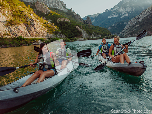 Image of A group of friends enjoying fun and kayaking exploring the calm river, surrounding forest and large natural river canyons during an idyllic sunset.