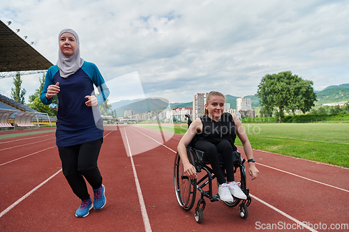 Image of A Muslim woman in a burqa running together with a woman in a wheelchair on the marathon course, preparing for future competitions.