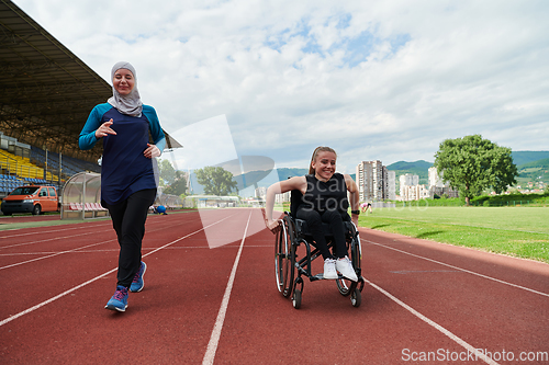 Image of A Muslim woman in a burqa running together with a woman in a wheelchair on the marathon course, preparing for future competitions.