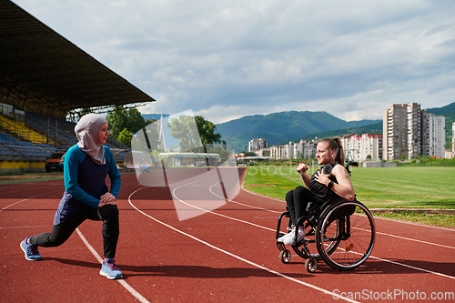 Image of Two strong and inspiring women, one a Muslim wearing a burka and the other in a wheelchair stretching and preparing their bodies for a marathon race on the track