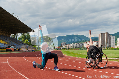 Image of Two strong and inspiring women, one a Muslim wearing a burka and the other in a wheelchair stretching and preparing their bodies for a marathon race on the track