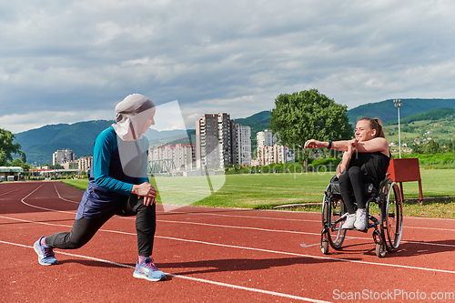 Image of Two strong and inspiring women, one a Muslim wearing a burka and the other in a wheelchair stretching and preparing their bodies for a marathon race on the track