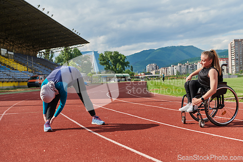 Image of Two strong and inspiring women, one a Muslim wearing a burka and the other in a wheelchair stretching and preparing their bodies for a marathon race on the track