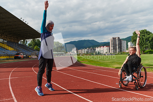 Image of Two strong and inspiring women, one a Muslim wearing a burka and the other in a wheelchair stretching and preparing their bodies for a marathon race on the track