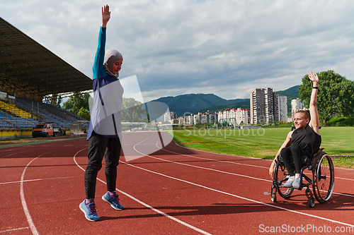 Image of Two strong and inspiring women, one a Muslim wearing a burka and the other in a wheelchair stretching and preparing their bodies for a marathon race on the track