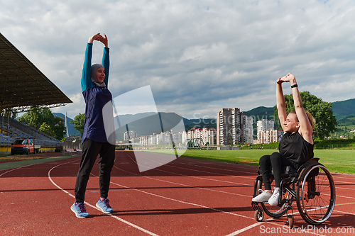 Image of Two strong and inspiring women, one a Muslim wearing a burka and the other in a wheelchair stretching and preparing their bodies for a marathon race on the track