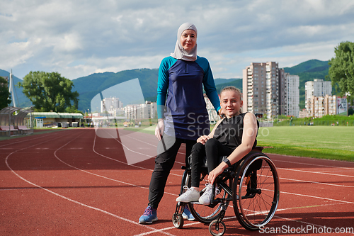 Image of A Muslim woman wearing a burqa resting with a woman with disability after a hard training session on the marathon course